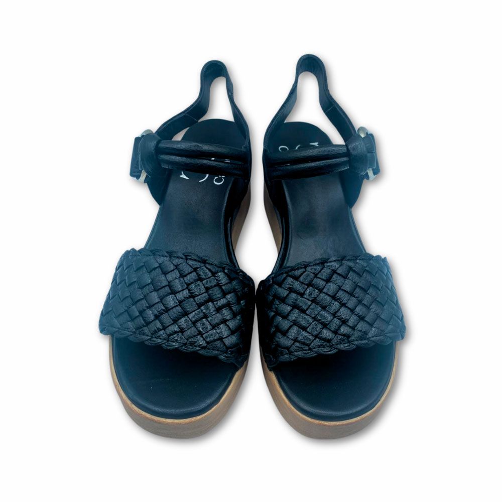 Frente sandalias negras con suela de cuña y plataforma bicolor de Plumers Menorca. Sandalias negras de piel con trenzado en el empeine, suela de cuña con plataforma de Plumers Menorca.