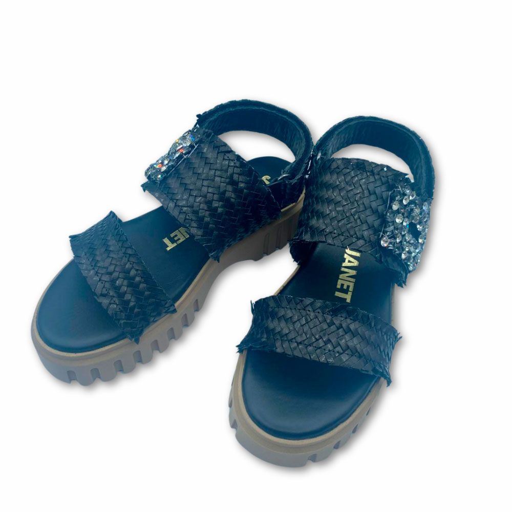 Costado sandalias negras de piel trenzada con plataforma de Janet&Janet. Sandalias negras de piel trenzada, con hebilla de brillos y tira al talón con velcro. Suela de plataforma de Janet&Janet.