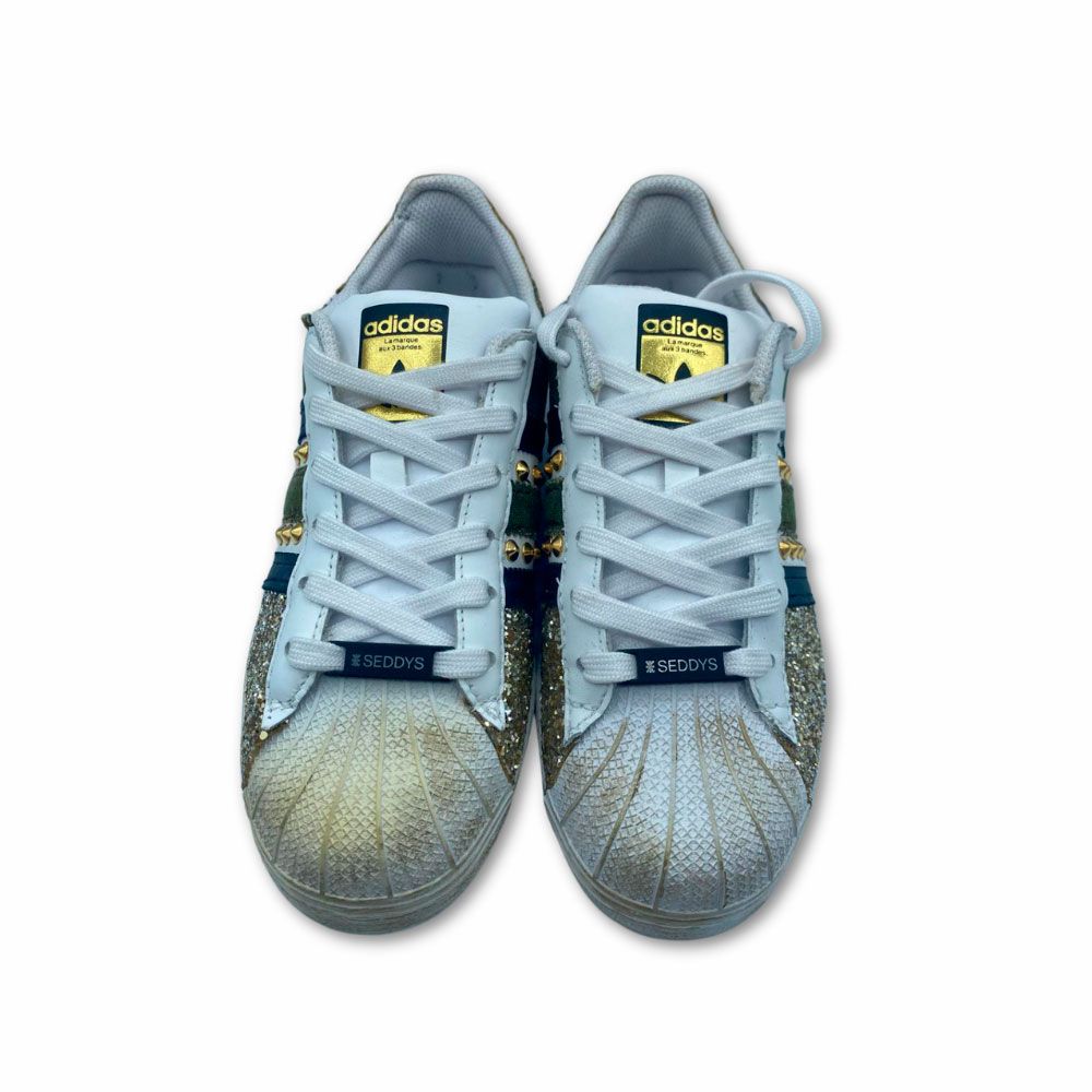 Frente originales zapatillas Adidas customizadas en dorado con brillo, remaches y estrella. Originales zapatillas Adidas customizadas con brillos, remaches y estrella dorados.